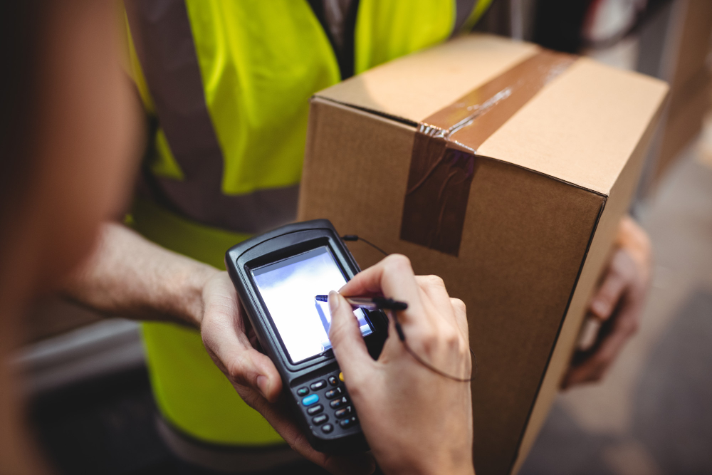 Cliente efetuando o pagamento através de sua assinatura para um armazém logístico que trabalha com picking e pacling.